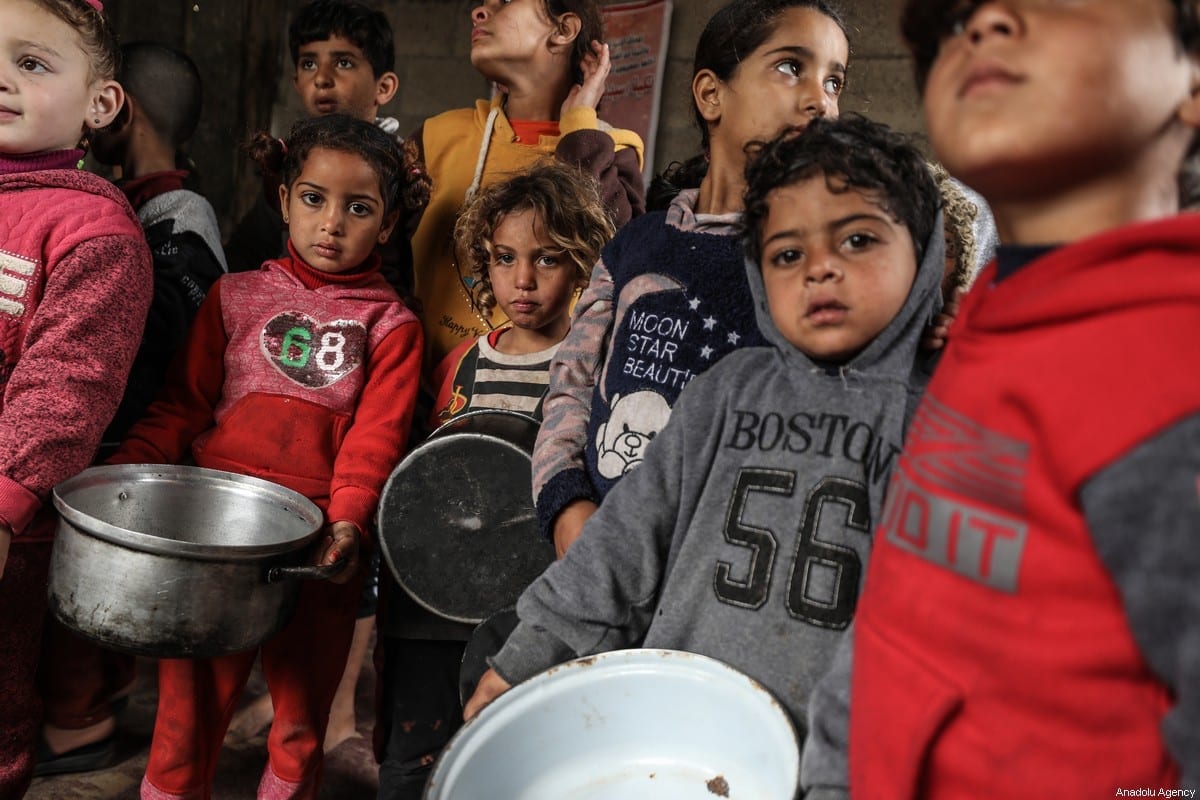 Crianças se reúnem para receber ajuda alimentar distribuída por uma benfeitora a famílias carentes no bairro de Zeitoun, na Cidade de Gaza, Gaza, em 28 de janeiro de 2021. [Ali Jadallah/Agência Anadolu]