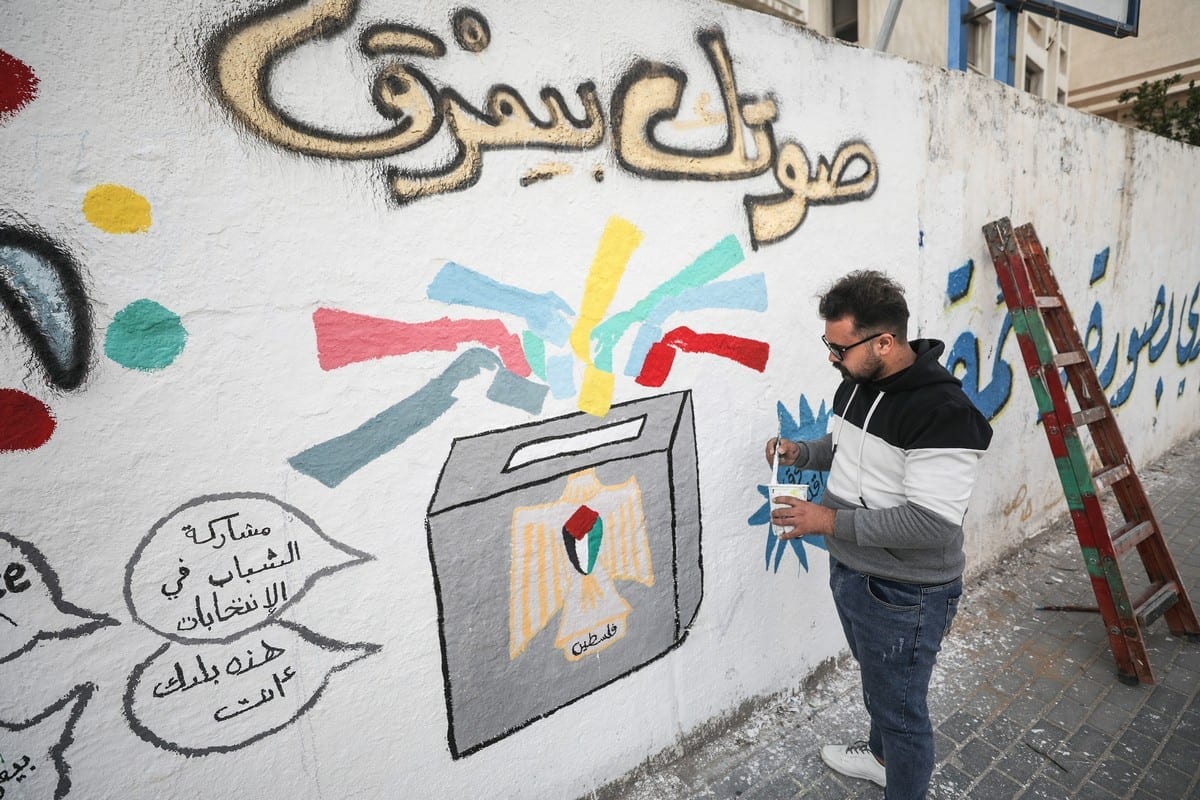 Artista palestino pinta um grafite sobre as eleições em uma parede antes das eleições para o Conselho Legislativo Palestino na Cidade de Gaza, Gaza, em 24 de março de 2021. [Mustafa Hassona/Agência Anadolu]