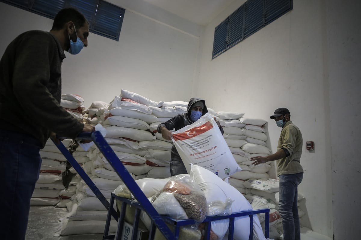 Trabalhadores da Agência das Nações Unidas de Assistência aos Refugiados da Palestina (UNRWA) organizam pacotes de ajuda humanitária de diversos países para distribuí-los em Jabalia, Faixa de Gaza, 17 de dezembro de 2020 [Ali Jadallah/Agência Anadolu]
