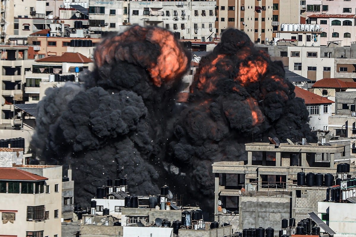 Fumaça e chamas aumentam após um ataque a um prédio atingido pelo exército israelense, na Cidade de Gaza, Gaza em 14 de maio de 2021 [Ali Jadallah/Agência Anadolu]
