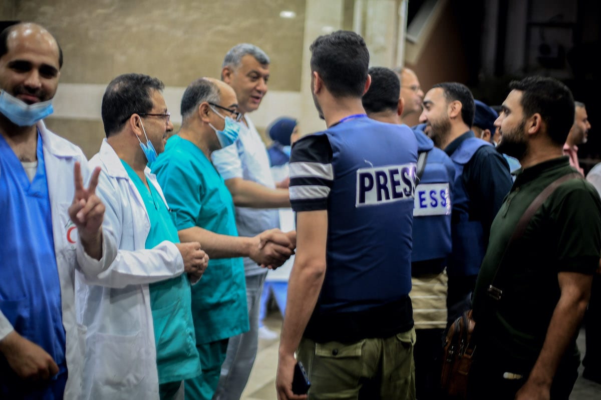 Membros da imprensa palestina e profissionais de saúde se reúnem para uma celebração após o acordo de cessar-fogo “mútuo e simultâneo” entre Israel e o Hamas que entrou em vigor às 2h da manhã de sexta-feira do horário local, encerrando o conflito de 11 dias, em Khan Yunis, Gaza, em 21 de maio 2021 [Abed Zagout/Agência Anadolu]
