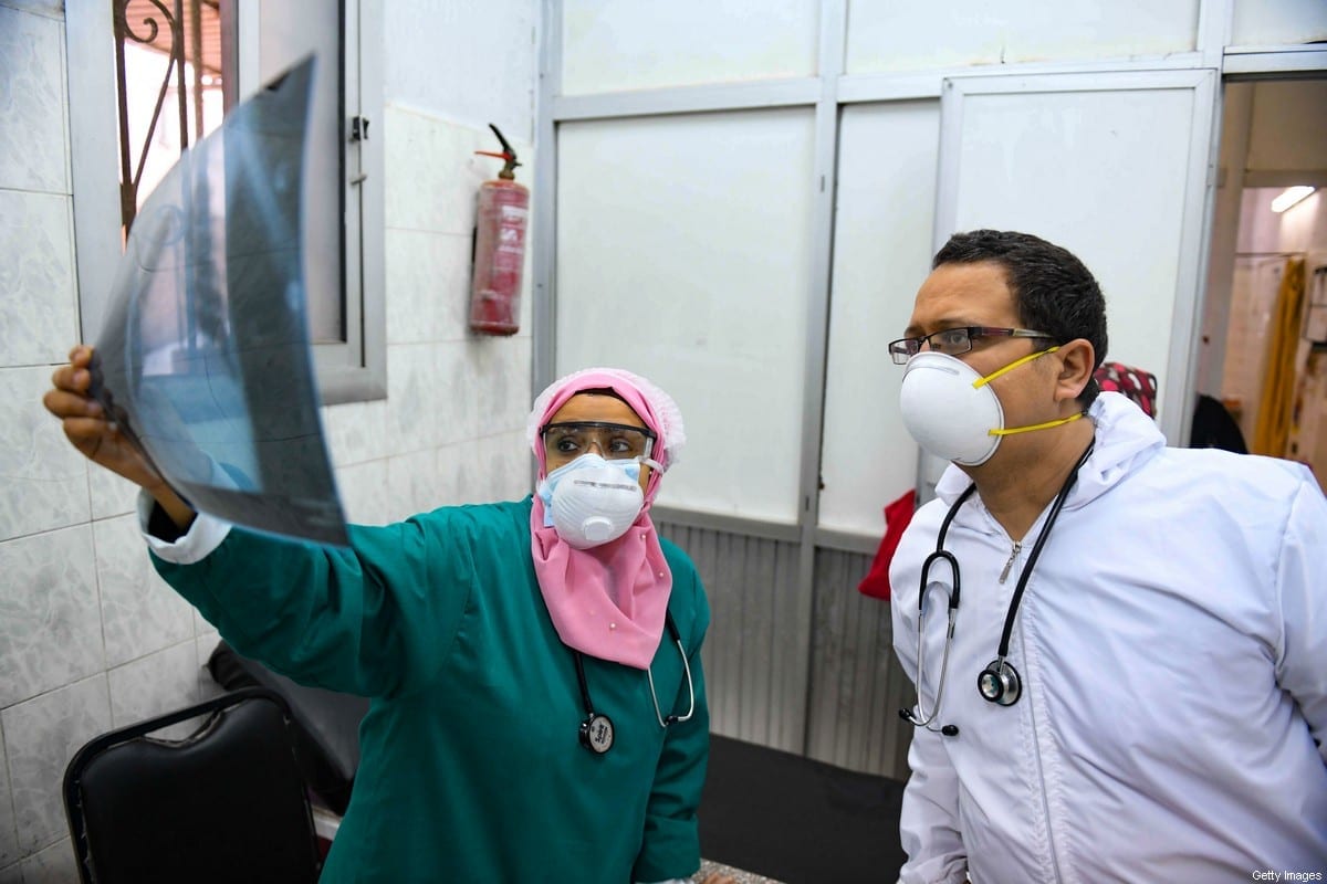 Médicos egípcios verificam radiografia pulmonar de um paciente na unidade de doenças infecciosas do hospital Imbaba, na capital Cairo, em 19 de abril de 2020, durante a nova crise de pandemia de coronavírus [Ahmed Hasan/AFP via Getty Images]
