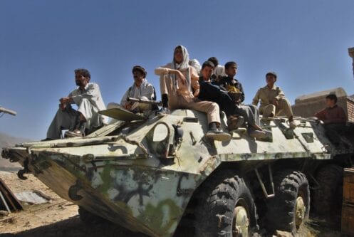 Afegãos sentam-se sobre um tanque soviético abandonado no Vale do Panjshir, em 10 de setembro de 2006 [Shah Marai/AFP via Getty Images]