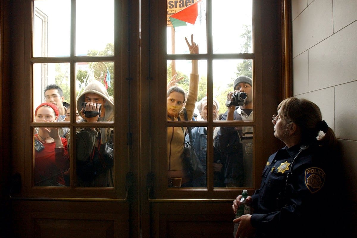 A policial Debra Schnek da Universidade da Califórnia em Berkeley guarda a porta de um prédio onde dezenas de manifestantes pró-palestinos fizeram uma manifestação, em 9 de abril de 2002, na escola em Berkeley, CA [Justin Sullivan/Getty Images]
