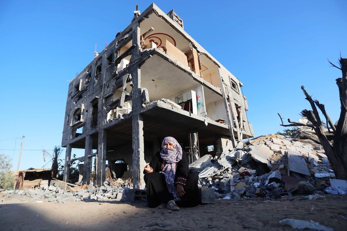 Uma senhora palestina senta-se em frente às ruínas de uma casa destruída pelos recentes bombardeios israelenses na Faixa de Gaza, em 7 de junho de 2021 [Ashraf Amra/Agência Anadolu]
