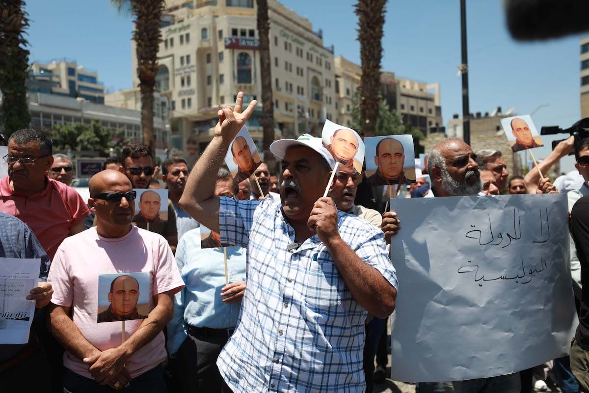 Um grupo de palestinos segurando faixas se reúne para protestar contra a morte de Nizar Banat, em 24 de junho de 2021, em Ramallah, na Cisjordânia [Issam Rimawi/Agência Anadolu]
