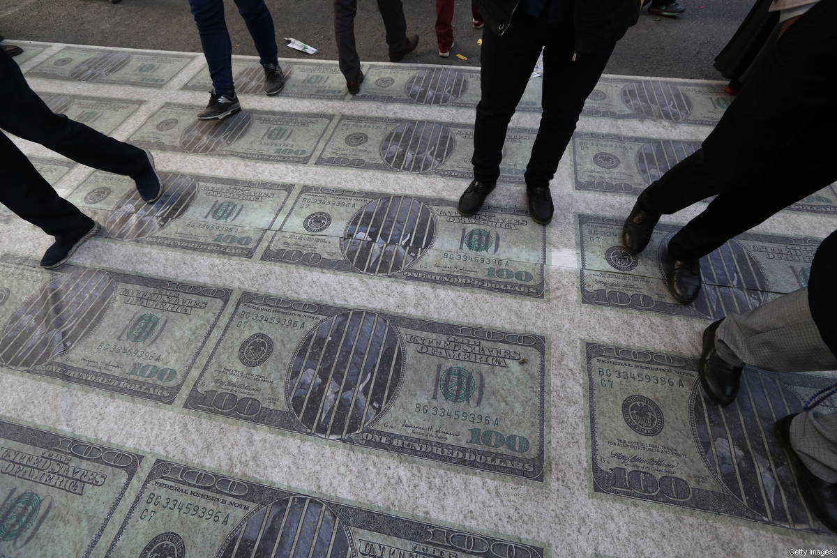 Manifestantes iranianos pisam sobre impressões enormes de imagens de notas de 100 dólares durante uma manifestação em frente à ex-embaixada dos EUA na capital Teerã em 4 de novembro de 2018 [Atta Kenare/AFP/Getty Images]
