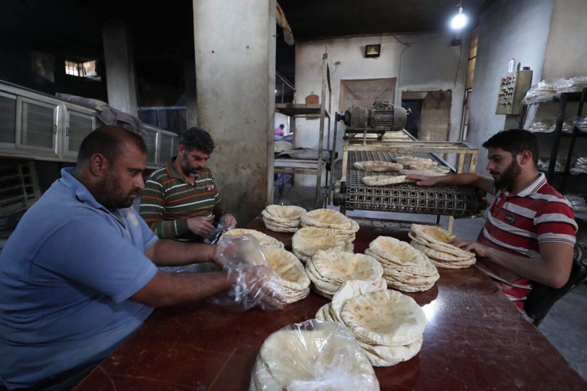 Sírios embalam pão em uma padaria na cidade de Binnish, na província de Idlib, no noroeste do país, em 9 de junho de 2020 [OMAR HAJ KADOUR/AFP via Getty Images]
