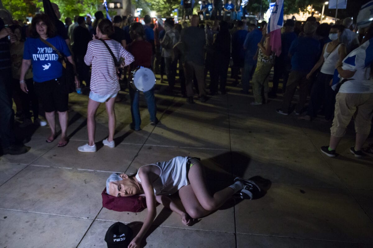 Mulher israelense com uma máscara do primeiro-ministro israelense, Benjamin Netanyahu, deita-se no chão durante um protesto em apoio a um governo de unidade para expulsar Netanyahu do cargo em 31 de maio de 2021 em Tel Aviv, Israel [Amir Levy/Getty Images]
