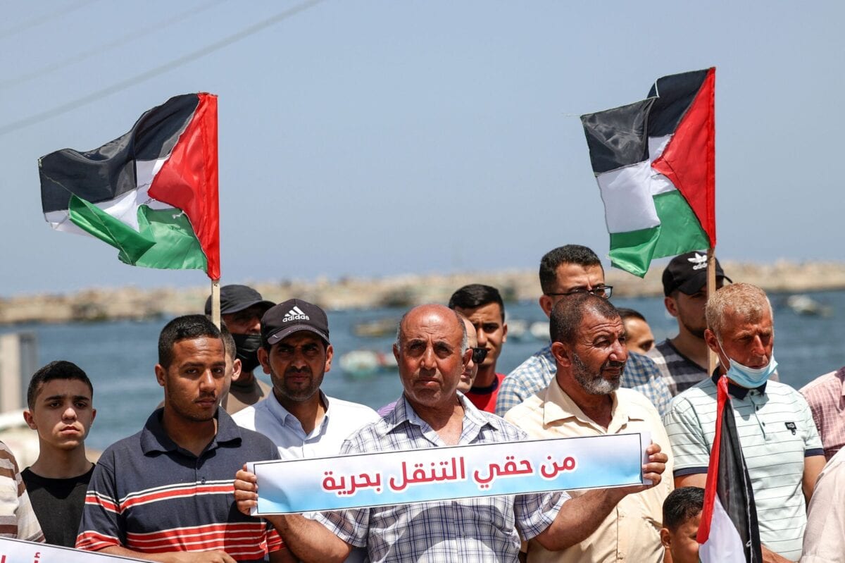 Pescadores palestinos protestam no porto de Gaza contra a redução por parte de Israel da área de pesca para seis milhas náuticas, na Cidade de Gaza, em 13 de junho de 2021. A faixa diz em árabe: 'Eu tenho o direito de navegar' [Mahmud Hams/ AFP via Getty Images] 
