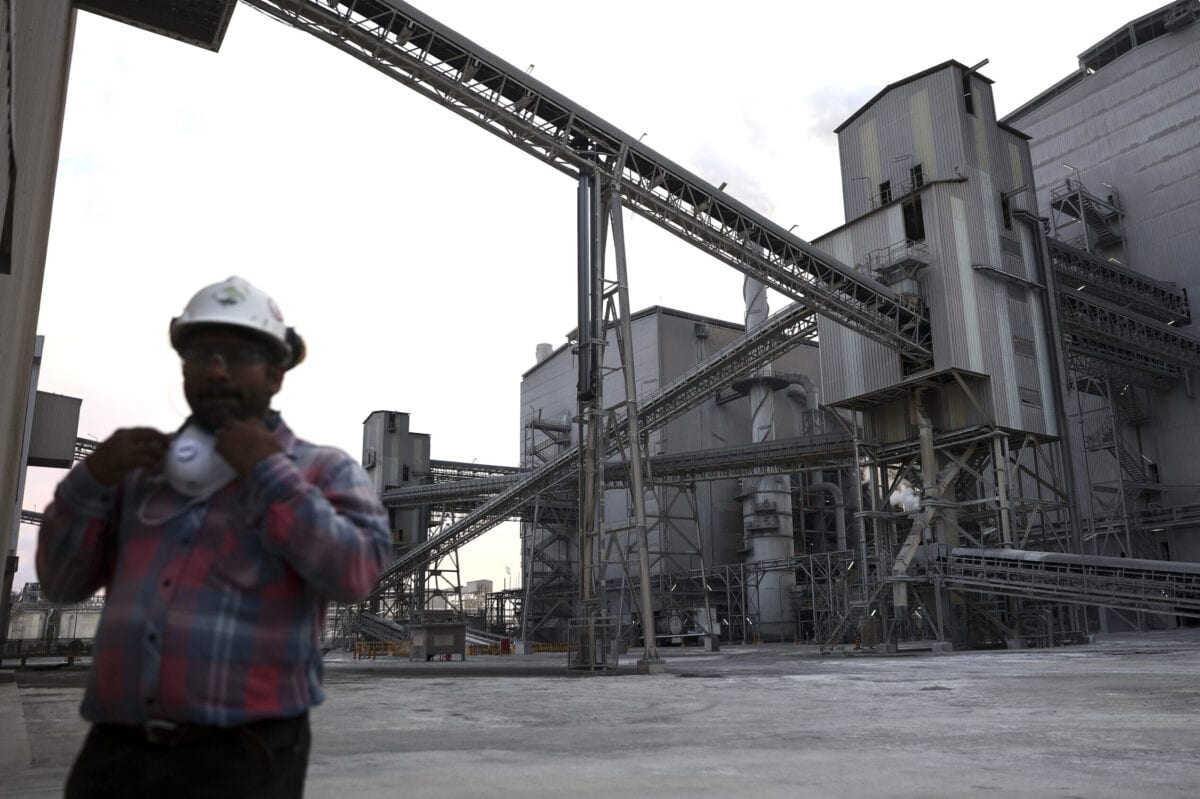 Um funcionário passa por um sistema de transporte de fosfato de diamônio (DAP) para a planta de processamento na Ras Al Khair Industrial City, operada pela Saudi Arabian Mining Co, em Ras Al Khair, Arábia Saudita, em 23 de novembro de 2016 [Simon Dawson/Bloomberg via Getty Images]
