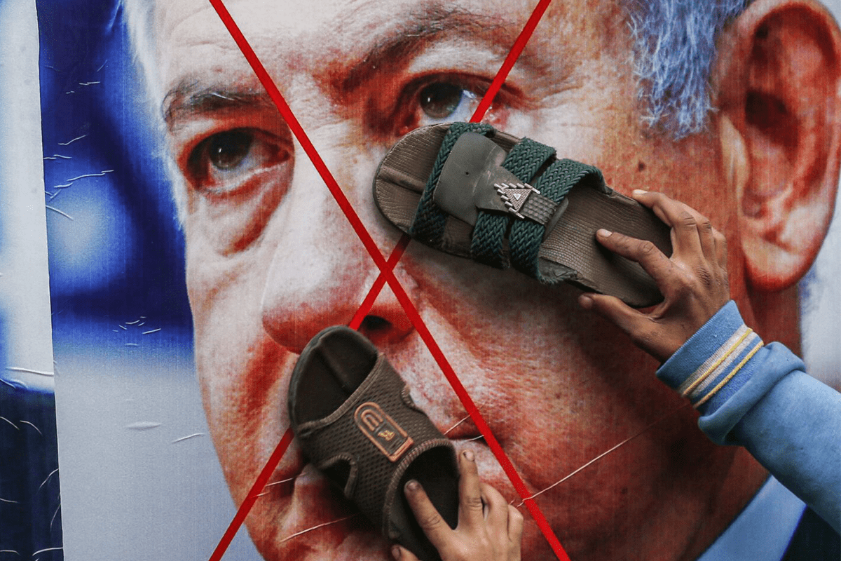 Manifestantes palestinos colam seus calçados em pôsteres que retratam os rostos do primeiro-ministro israelense, Benjamin Netanyahu, em 3 de fevereiro de 2020 [Said Khatib/AFP via Getty Images]
