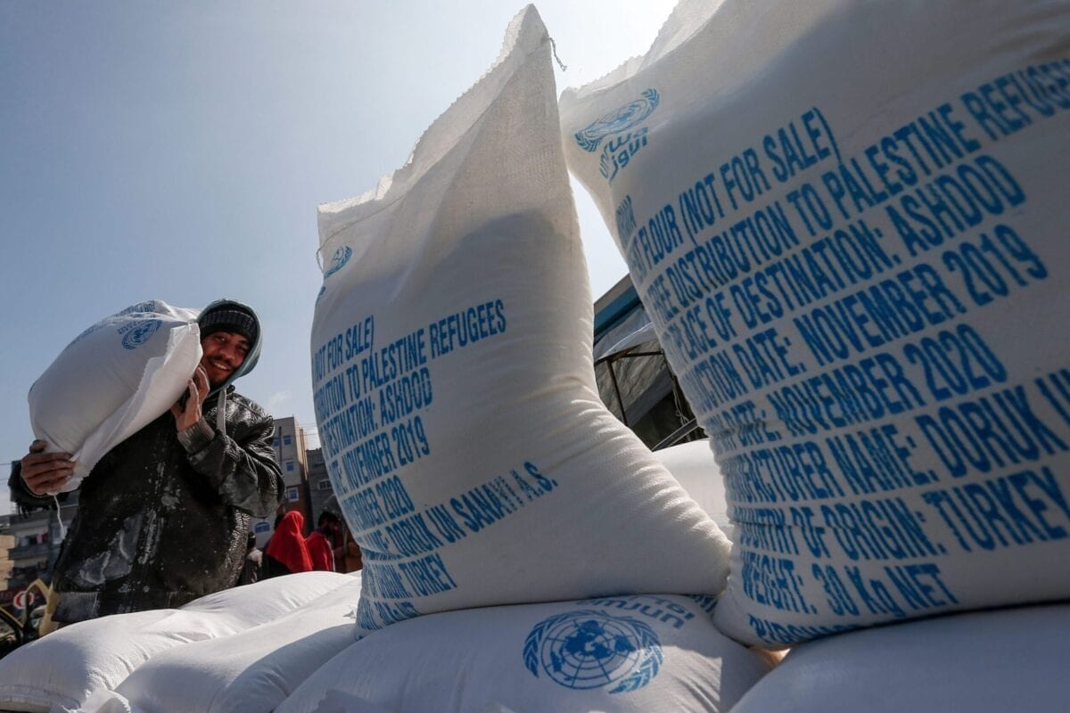 Um homem palestino carrega nos ombros sacos de farinha recebidos de um centro de distribuição da UNRWA no campo de refugiados de Jabalia, no norte da Faixa de Gaza, em 29 de janeiro de 2020 [Mahmud Hams/AFP via Getty Images]