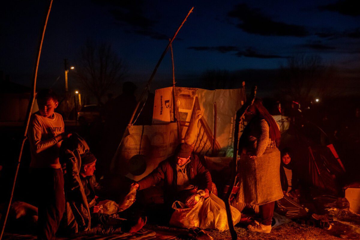 Um homem entrega um pacote de ajuda aos refugiados do Afeganistão em um acampamento onde refugiados e migrantes de vários países esperam na costa turca do rio Evros para cruzar de barco para a Grécia, em 03 de março de 2020, em Edirne, Turquia [Chris McGrath/Getty Images]
