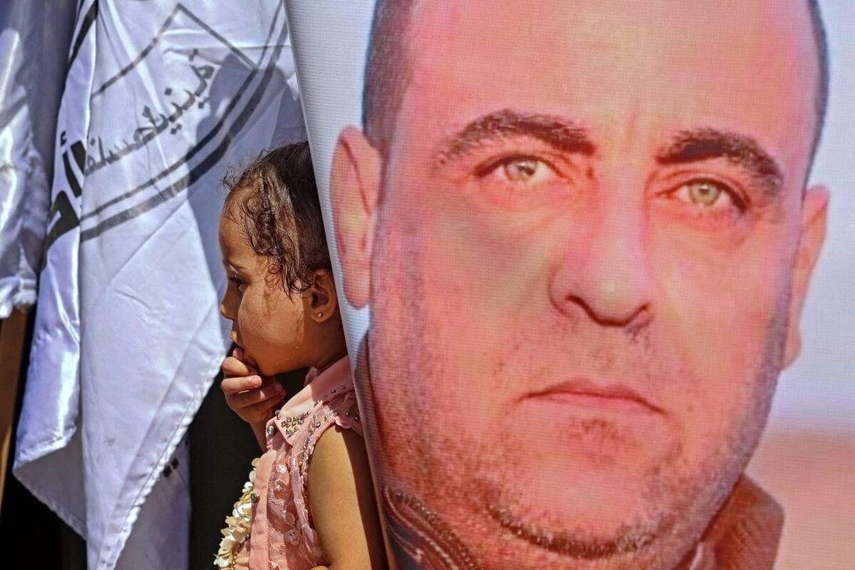 Uma garota está atrás de cartazes que retratam o falecido ativista palestino de direitos humanos Nizar Banat durante uma manifestação em memória dele na Cidade de Gaza em 29 de junho de 2021 [MOHAMMED ABED / AFP via Getty Images]
