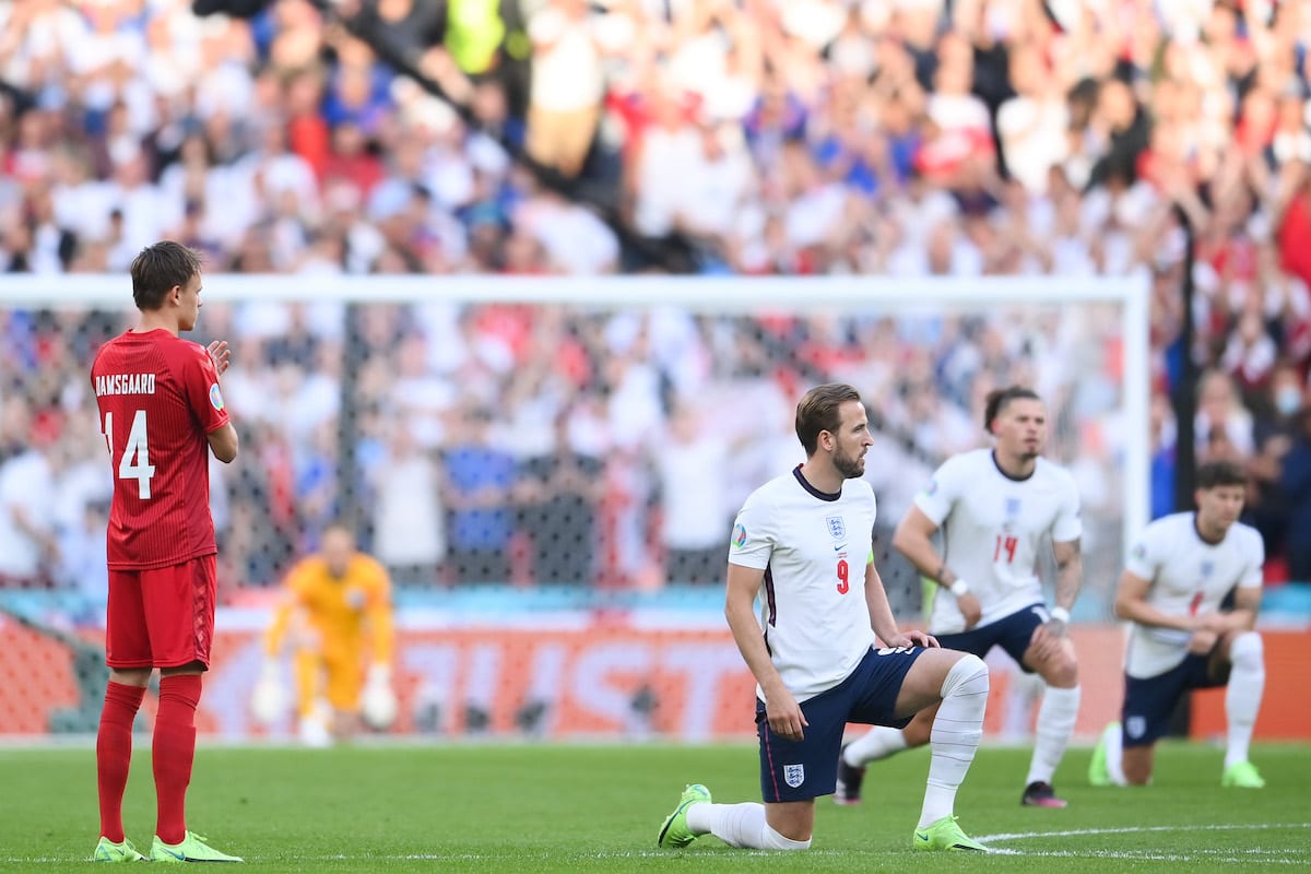 Harry Kane, centroavante da Inglaterra, ajoelha-se em apoio ao Black Lives Matter, antes da semifinal do Campeonato Europeu de Futebol de 2020 (UEFA Euro 2020) contra a seleção da Dinamarca, no Estádio de Wembley, em Londres, 7 de julho de 2021 [Laurence Griffiths/Getty Images]
