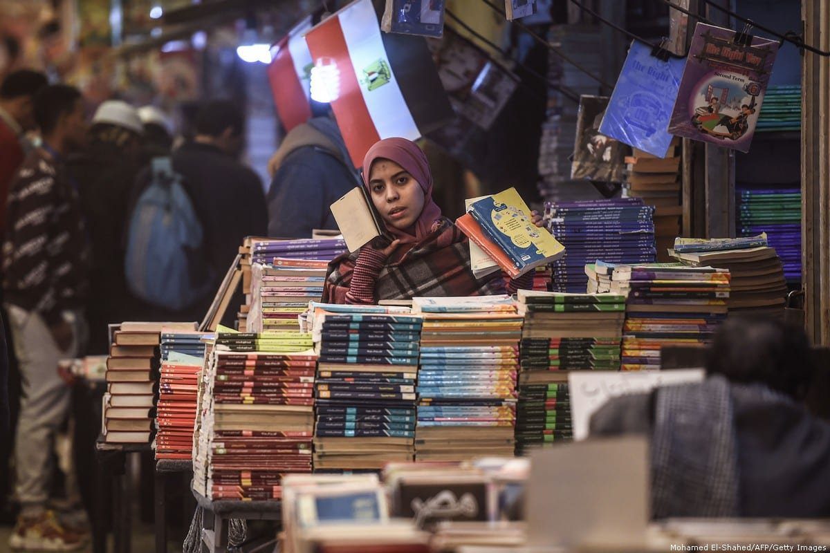 Uma mulher fala ao celular enquanto escolhe uma seleção de livros no histórico mercado de livros al-Azbakeya, no Cairo, no centro do Cairo, em 16 de janeiro de 2019 [Mohamed El-Shahed/AFP/Getty Images]

