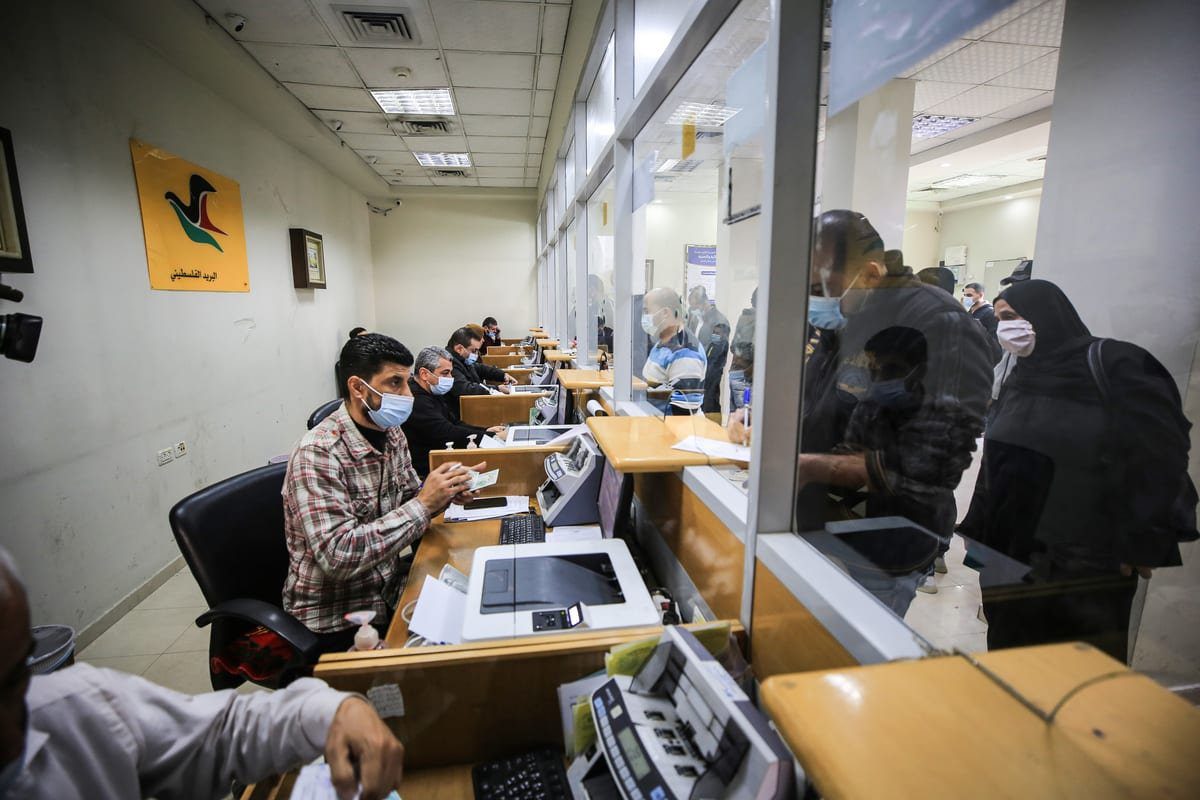 Palestinos recebem ajuda financeira do Catar em uma agência dos correios na Cidade de Gaza, 30 de dezembro de 2020 [Ali Jadallah/Agência Anadolu]
