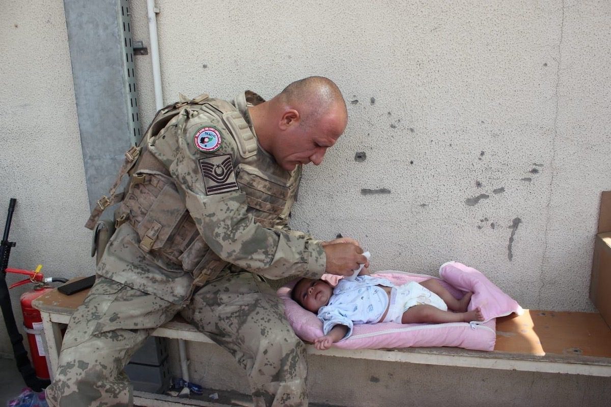 Soldado turco cuida de um bebê enquanto espera a evacuação no Aeroporto Internacional Hamid Karzai em Cabul, Afeganistão, em 21 de agosto de 2021 [Ministério da Defesa Nacional TUR/Agência Anadolu]
