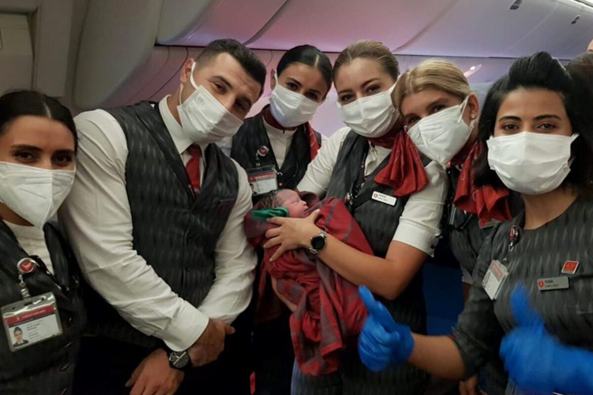 Tripulação posa com um bebê que nasceu a bordo do voo de evacuação da Turkish Airlines Dubai-Birmingham, a 10 mil metros de altitude, em 28 de agosto de 2021 [Turkish Airlines/Agência Anadolu]