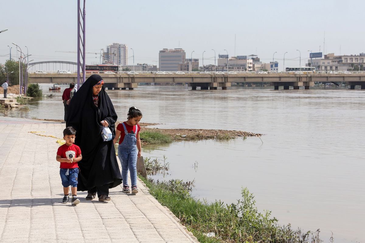 Uma mulher caminha com seus filhos ao longo do rio Karun, que rompeu suas margens em Ahvaz, capital da província de Khuzistão, no sudoeste do Irã, em 11 de abril de 2019 [Atta Kenare/AFP via Getty Images]
