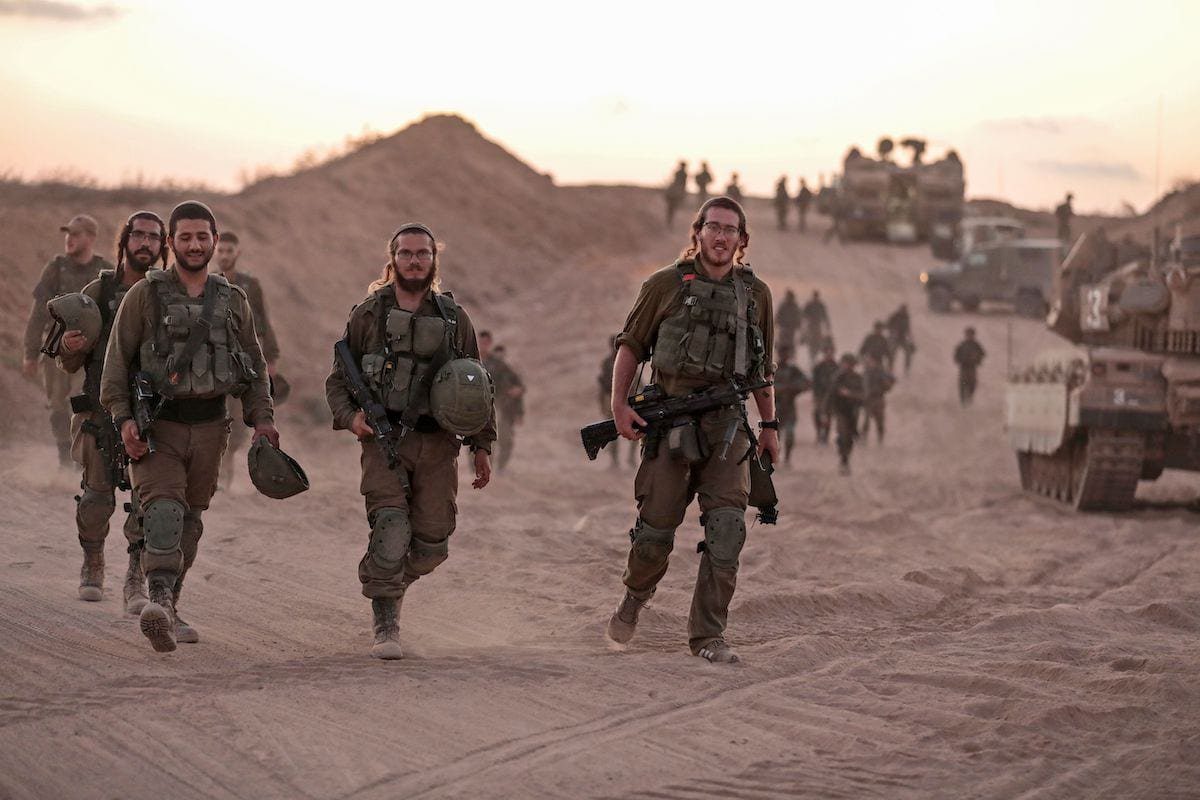 Soldados da infantaria israelense caminham ao lado de tanques e veículos blindados perto da fronteira israelense com a Faixa de Gaza, em 16 de agosto de 2020 [Menahem Kahana/AFP via Getty Images]
