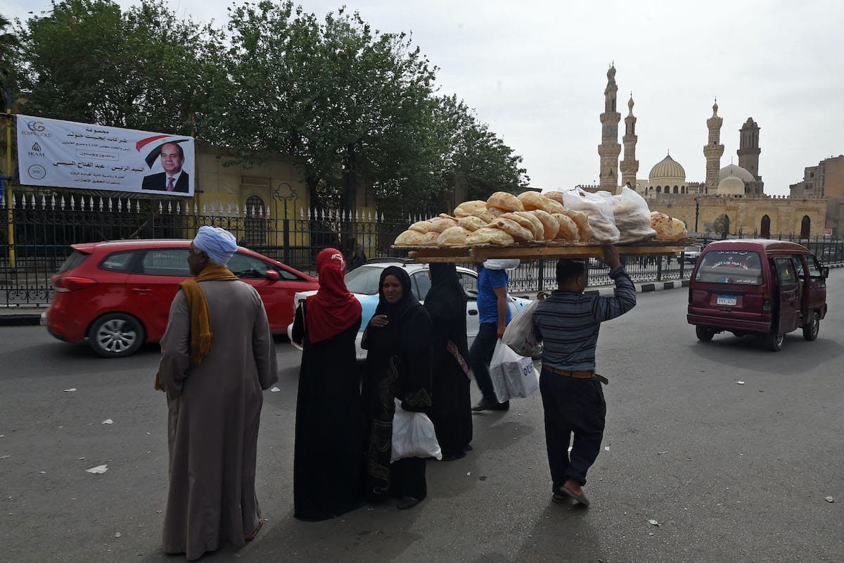 Um vendedor de pão caminha em frente à Mesquita Al-Azhar, no centro do Cairo, em 23 de março de 2018 [Fethi Belaid/AFP via Getty Images]
