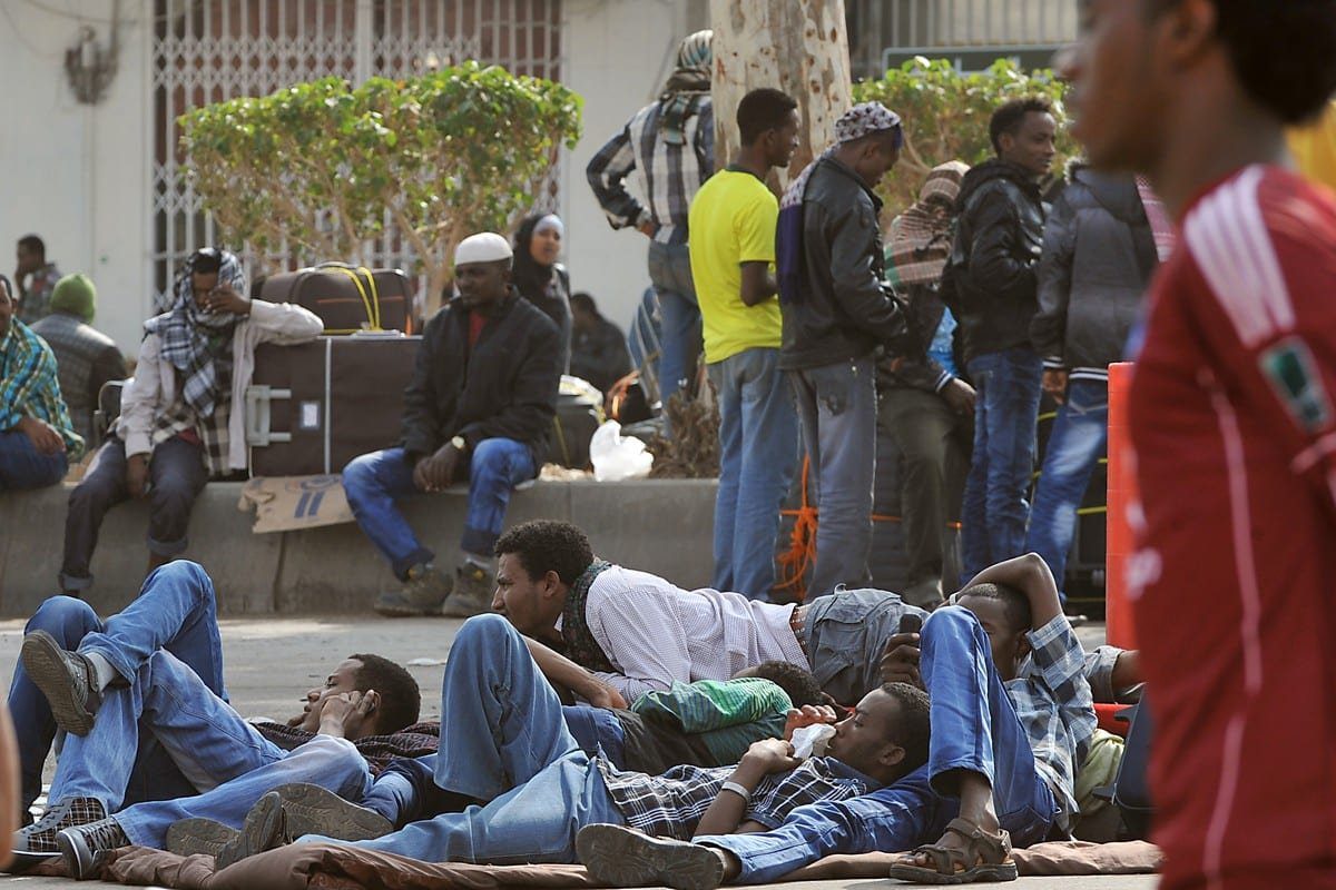 Trabalhadores estrangeiros esperam com seus pertences antes de embarcarem nos ônibus da polícia que os transferem para um centro de deportação em Riad, Arábia Saudita, em 14 de novembro de 2013 [Fayez Nureldine/AFP/Getty Images]
