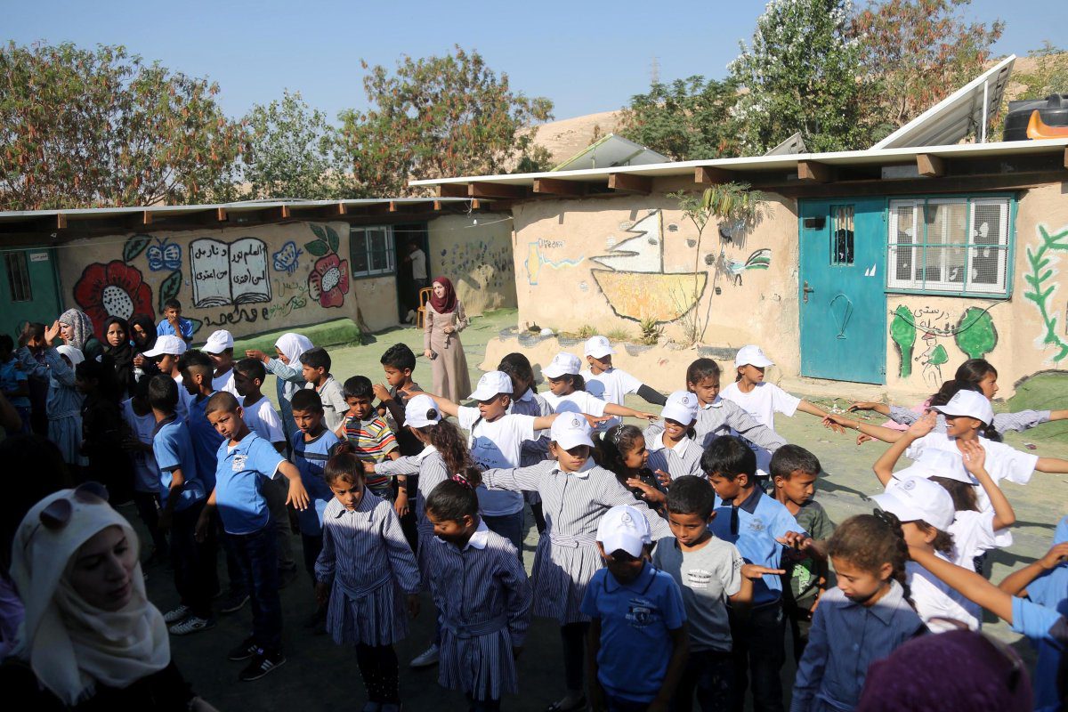 Crianças beduínas esperam em fila na única escola da região de Khan al-Ahmar, em Jerusalém ocupada, 16 de julho de 2018 [Issam Rimawi/Agência Anadolu]

