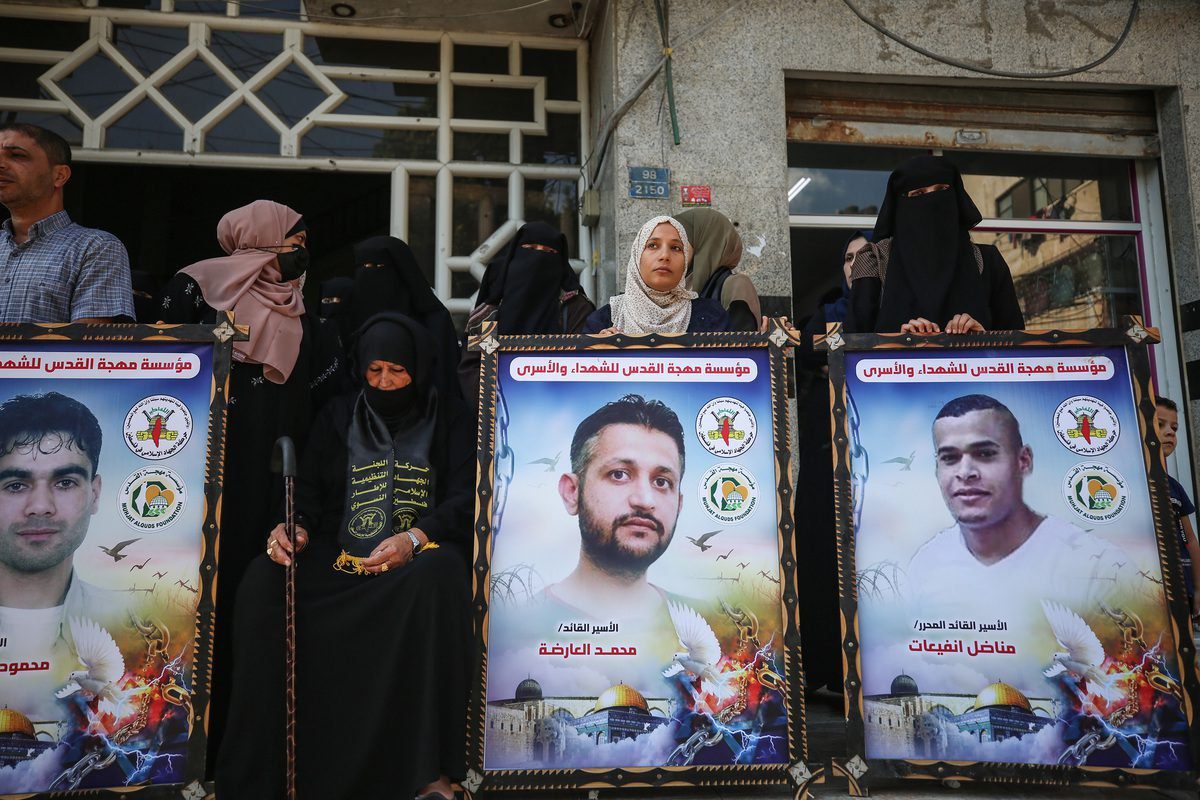 Manifestantes exibem cartazes com retrato dos palestinos que escaparam da penitenciária de Gilboa, em ato de solidariedade aos prisioneiros palestinos nas cadeias de Israel, na Cidade de Gaza, 25 de setembro de 2021 [Mustafa Hassona/Agência Anadolu]
