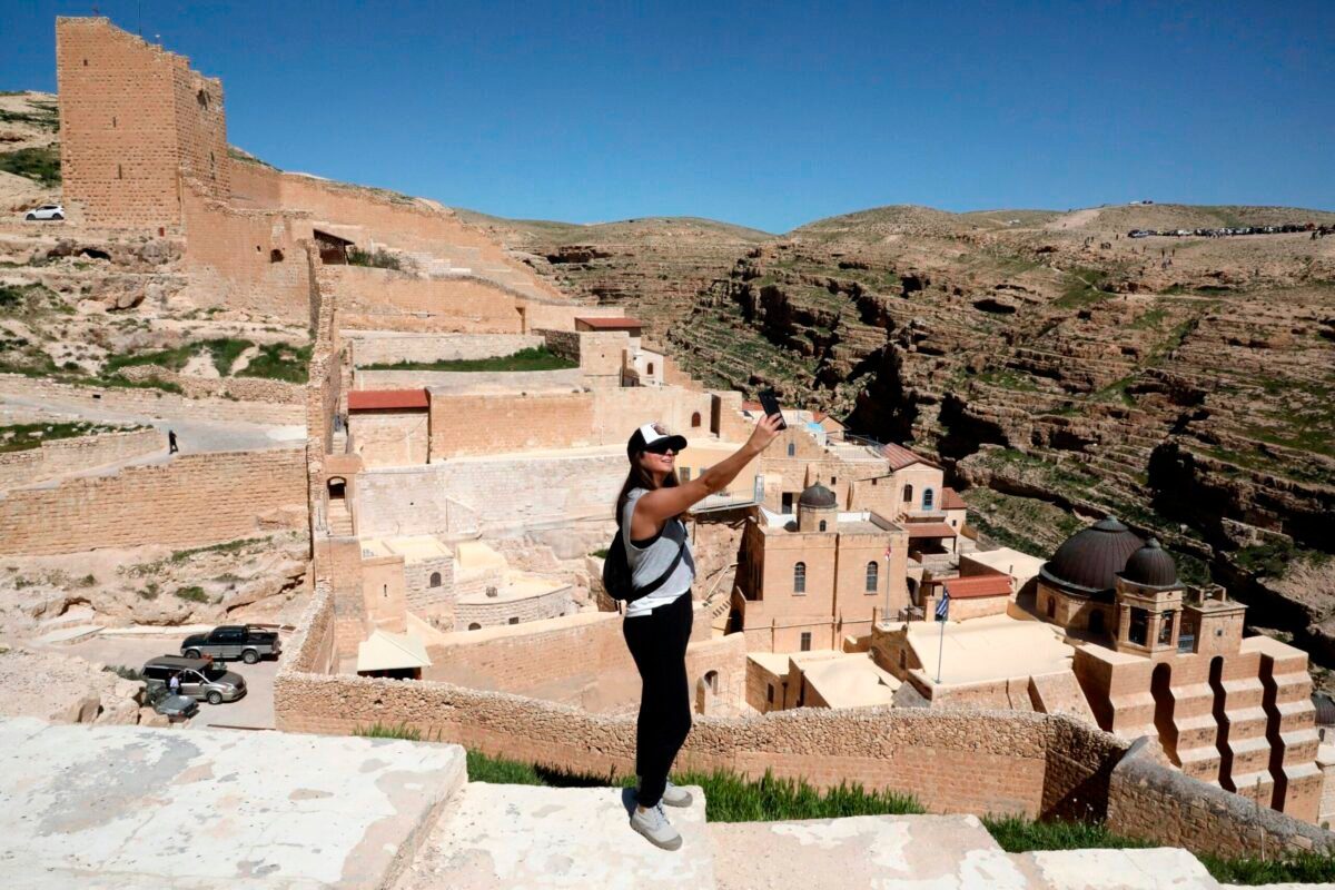 Turista tira uma 'selfie' em uma vista do mosteiro ortodoxo grego de Saint Sabbas (Mar Saba), com vista para o vale Kidron, ao sul da cidade bíblica de Belém na Cisjordânia, em 6 de março de 2021 [Hazem Bader/ AFP via Getty Images]
