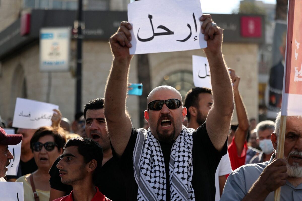 Manifestante palestino ergue placa em árabe escrito 'Fora!', em referência ao Presidente da Autoridade Palestina Mahmoud Abbas, durante ato na cidade de Ramallah, Cisjordânia ocupada, 11 de julho de 2021 [ABBAS MOMANI/AFP via Getty Images]
