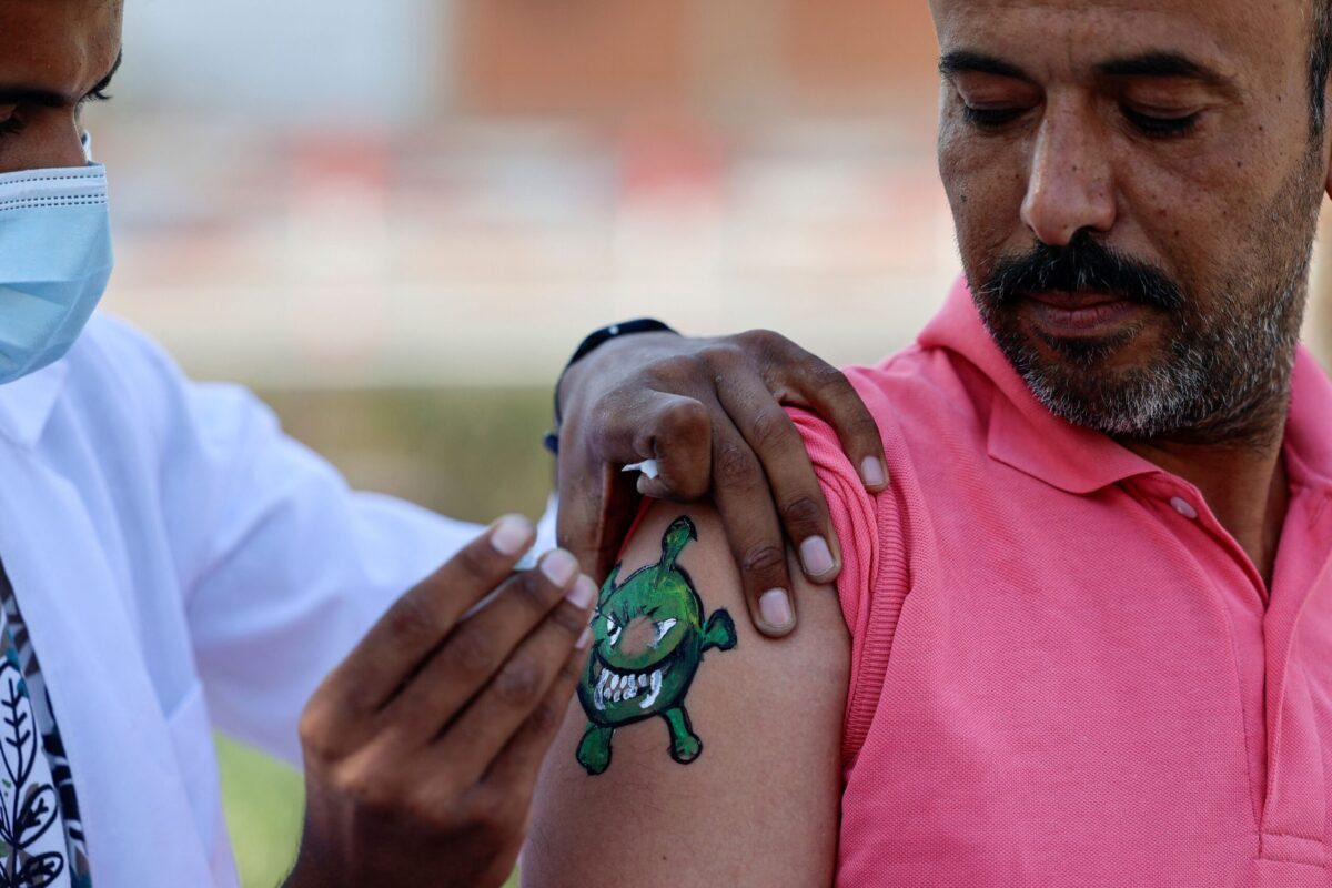 Um palestino recebe uma dose da vacina Sputnik-V contra o coronavírus, em um braço no qual um artista pintou um vírus, durante uma campanha de vacinação organizada pelo Ministério da Saúde, na Cidade de Gaza, em 1º de setembro de 2021 [Mohammed Abed/AFP via Getty Images]
