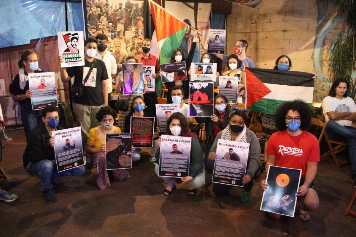 Participantes do ato em SP exibem cartazes com os nomes dos presos que fugiram da prisão israelense por um túnel e estavam sendo caçados e recapturados por Israel [Lucas Martins]