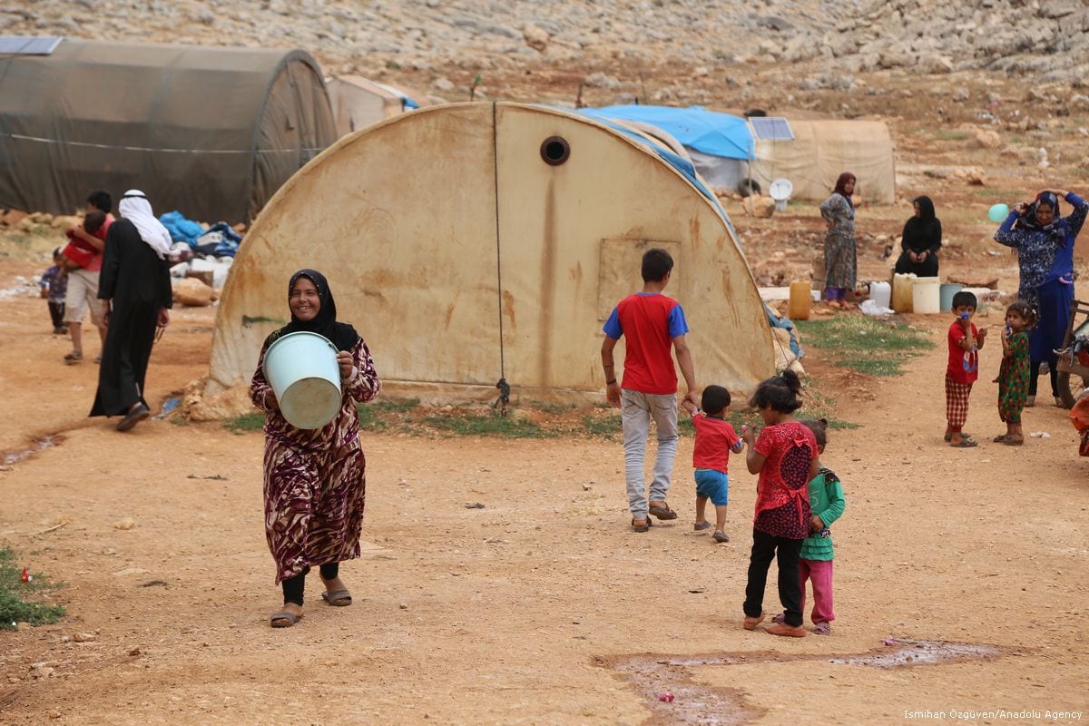 Mulher síria carrega balde para encher de água, às vésperas do feriado islâmico do Eid, em Idlib, norte da Síria, 23 de junho de 2017 [Ismihan Özgüven/Agência Anadolu]