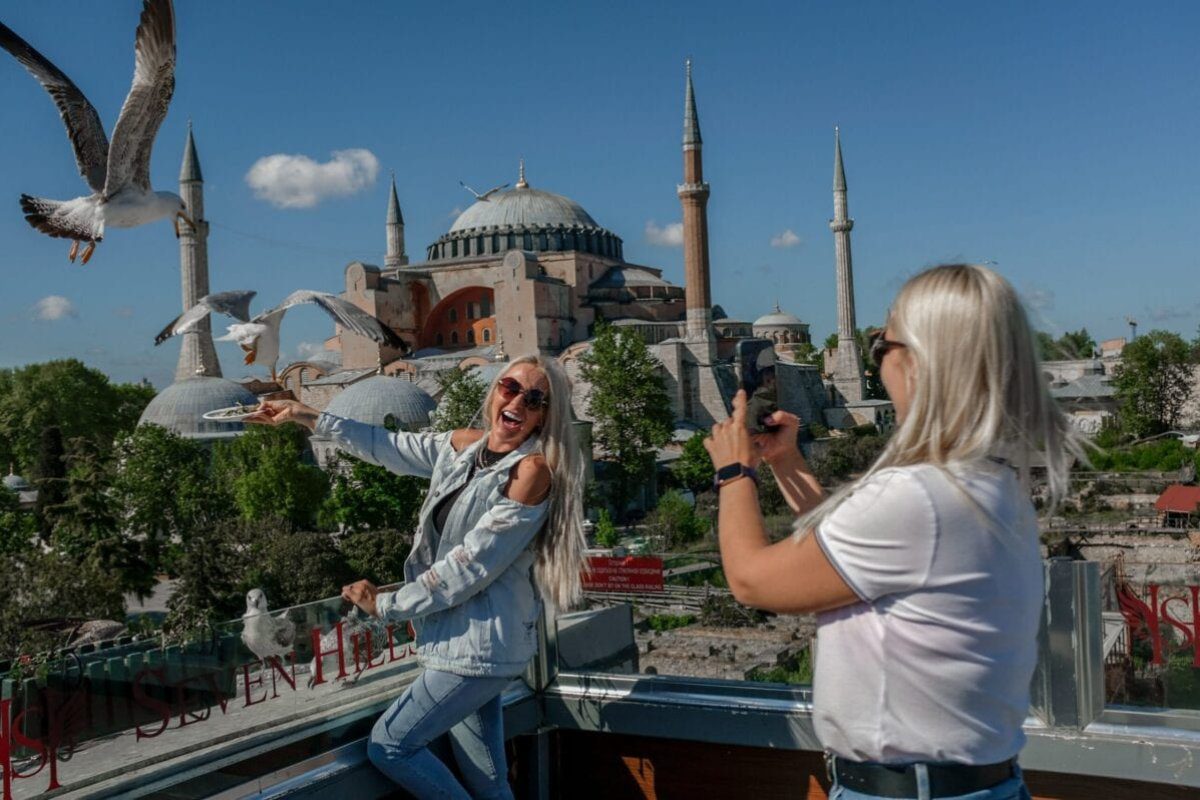 Turistas tirando fotos perto da Mesquita de Hagia Sophia em Sultanahmet em Istambul, em 9 de maio de 2021 [Bulent Kilic/AFP via Getty Images]
