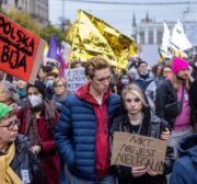 Um migrante sírio se senta sob cobertores de resgate para se proteger contra a chuva na floresta perto de Hajnowka, Polônia, durante uma operação de resgate conjunta de ativistas da "Grupa Granica" (Grupo de Fronteira) e voluntários de Medycy na Granicy (Médicos na Fronteira), em 23 de outubro de 2021 [Wojtek Radwanski/AFP via Getty Images]