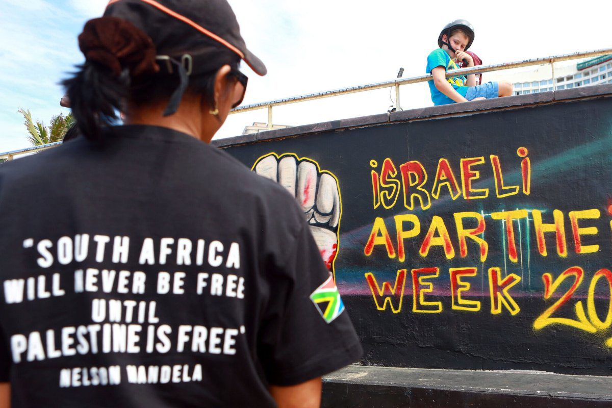 Ativistas palestinos ficam em frente a um graffiti, de 11 a 17 de março de 2013, na África do Sul [Rajesh Jayantilal/AFP via Getty Images]
