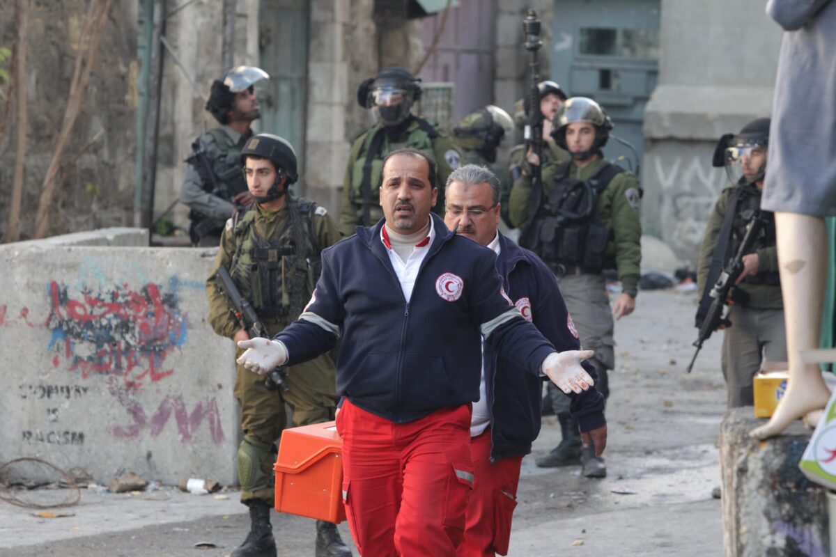 Forças de segurança israelenses ficam de guarda ao lado de membros do Crescente Vermelho Palestino na Cisjordânia, em 20 de dezembro de 2015 [Hazem Bader/AFP via Getty Images]
