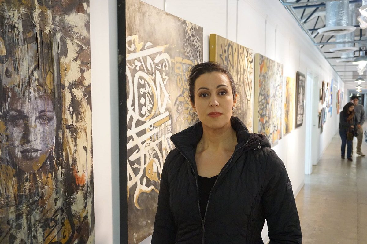 Artista Manal Deeb em frente às suas obras, em foto tirada para a Palestine Issue Magazine [Reprodução/Facebook] 
