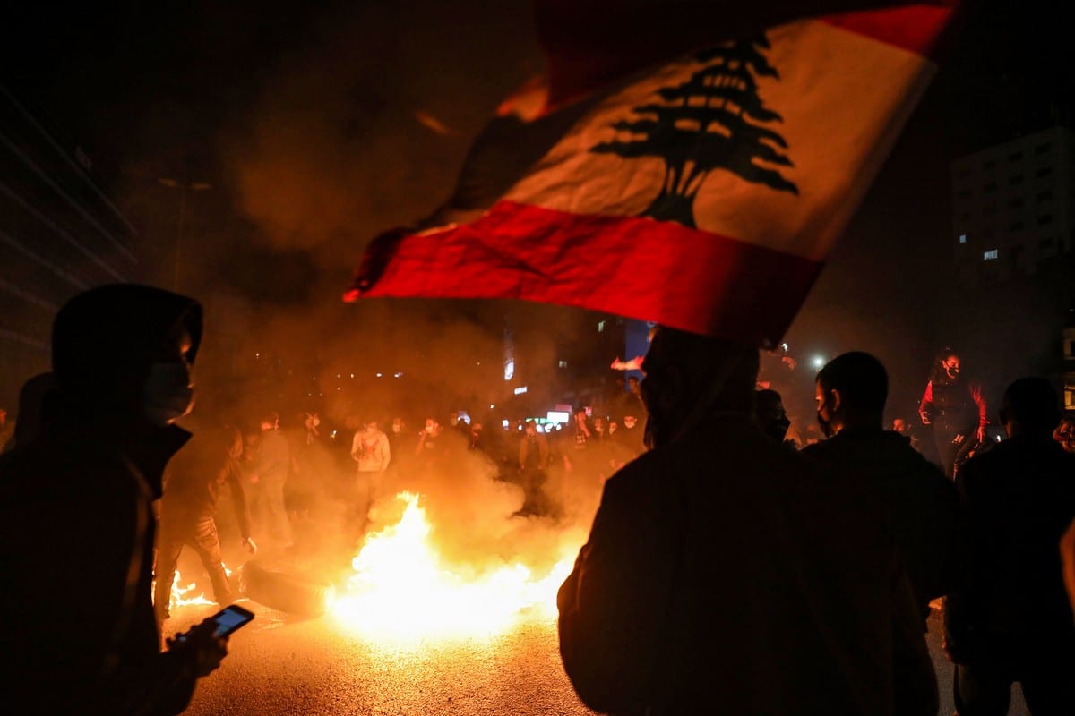 Manifestantes agitam a bandeira nacional libanesa em um protesto contra a deterioração das condições econômicas e sociais em Beirute, Líbano em 2 de março de 2021 [Anwar Amro/ AFP/ Getty Images]