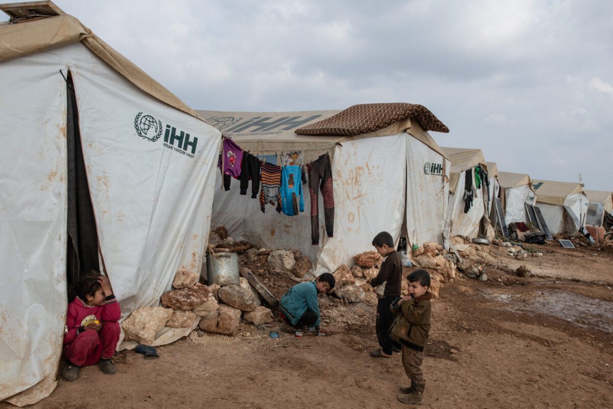 Crianças sírias deslocadas brincam em frente à sua tenda no acampamento Harana Bush da Fundação de Ajuda Humanitária (IHH), em 19 de fevereiro de 2020, em Idlib, Síria [Burak Kara/Getty Images]