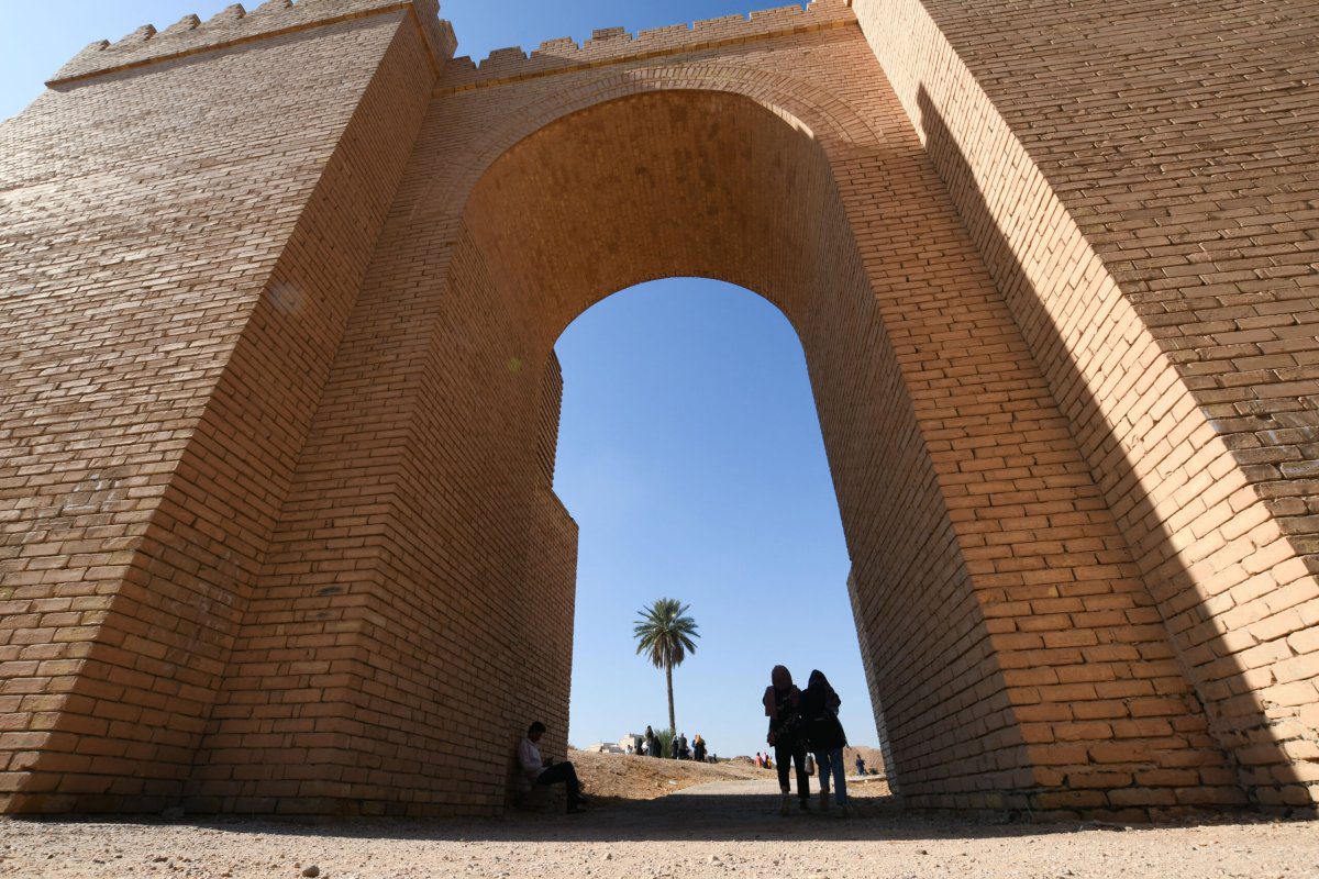 Os visitantes caminham por um portal no sítio arqueológico da antiga Babilônia, cerca de 100 km ao sul da capital iraquiana, em 14 de novembro de 2020 [Assaad Al-Niyazi/AFP via Getty Images]