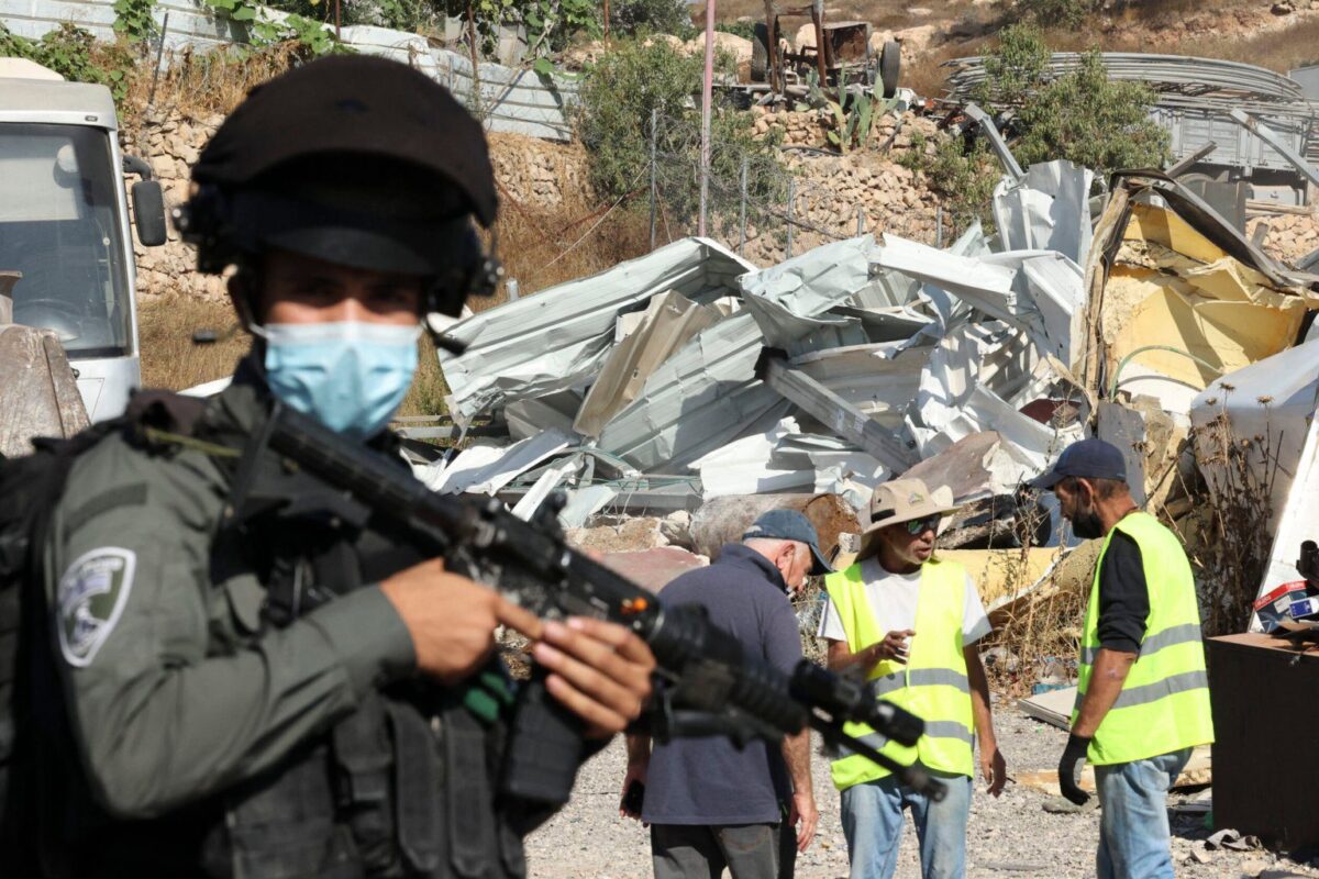 Uma escavadeira israelense destrói uma oficina de metal palestina construída na área "C", na cidade de Hebron, na Cisjordânia, em 25 de agosto de 2021 [Hazem Bader/AFP via Getty Images]
