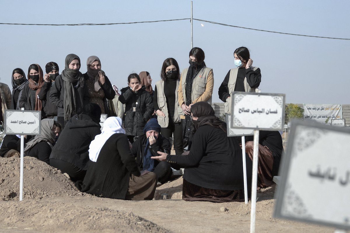 Mulheres choram junto a um túmulo durante um funeral em massa pelas vítimas yazidis do Daesh cujos restos mortais foram encontrados em uma vala comum, na aldeia iraquiana de Kojo, no distrito de Sinjar, em 9 de dezembro de 2021 [Zaid Al-Obeidi/AFP via Getty Images]