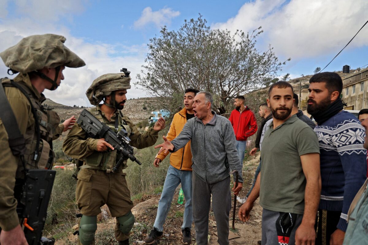 Residentes palestinos do vilarejo de Burqah, na Cisjordânia, enfrentam soldados israelenses em 17 de dezembro de 2021, após relatos de ataques por colonos israelenses no vilarejo [Jaafar Ashtiyeh/AFP via Getty Images]
