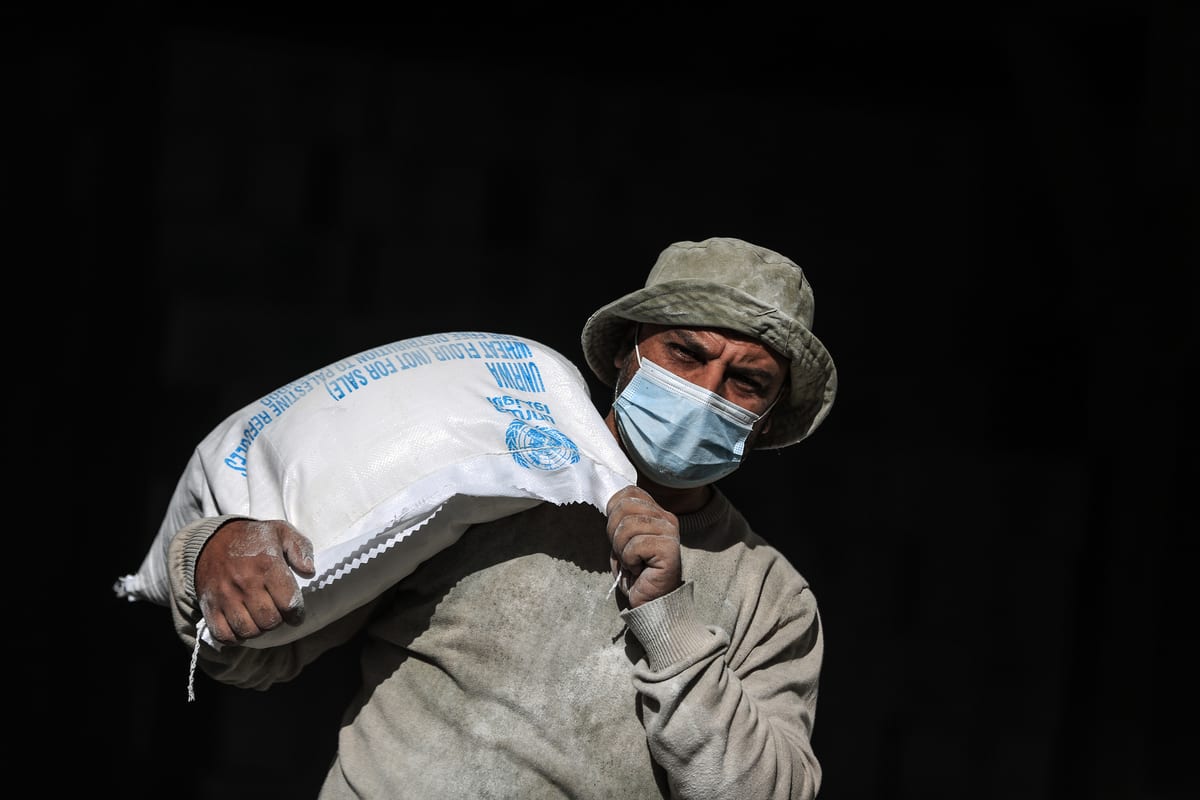 Trabalhadores da Agência das Nações Unidas de Assistência aos Refugiados da Palestina (UNRWA) distribuem pacotes assistenciais no campo de al-Shati, na Cidade de Gaza, 14 de janeiro de 2020 [Ali Jadallah/Agência Anadolu]
