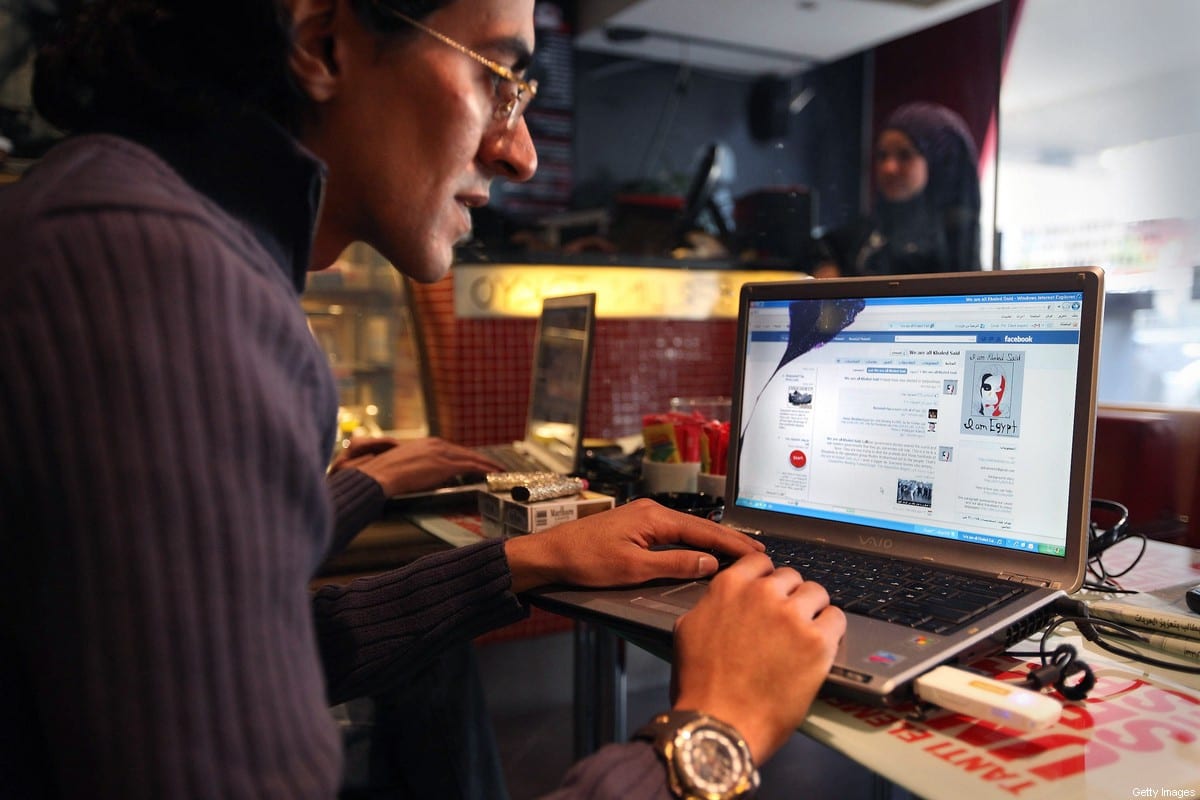 Um homem olha para um laptop exibindo uma página do Facebook em um café, em 27 de janeiro de 2011 no Cairo, Egito [Peter Macdiarmid/Getty Images]