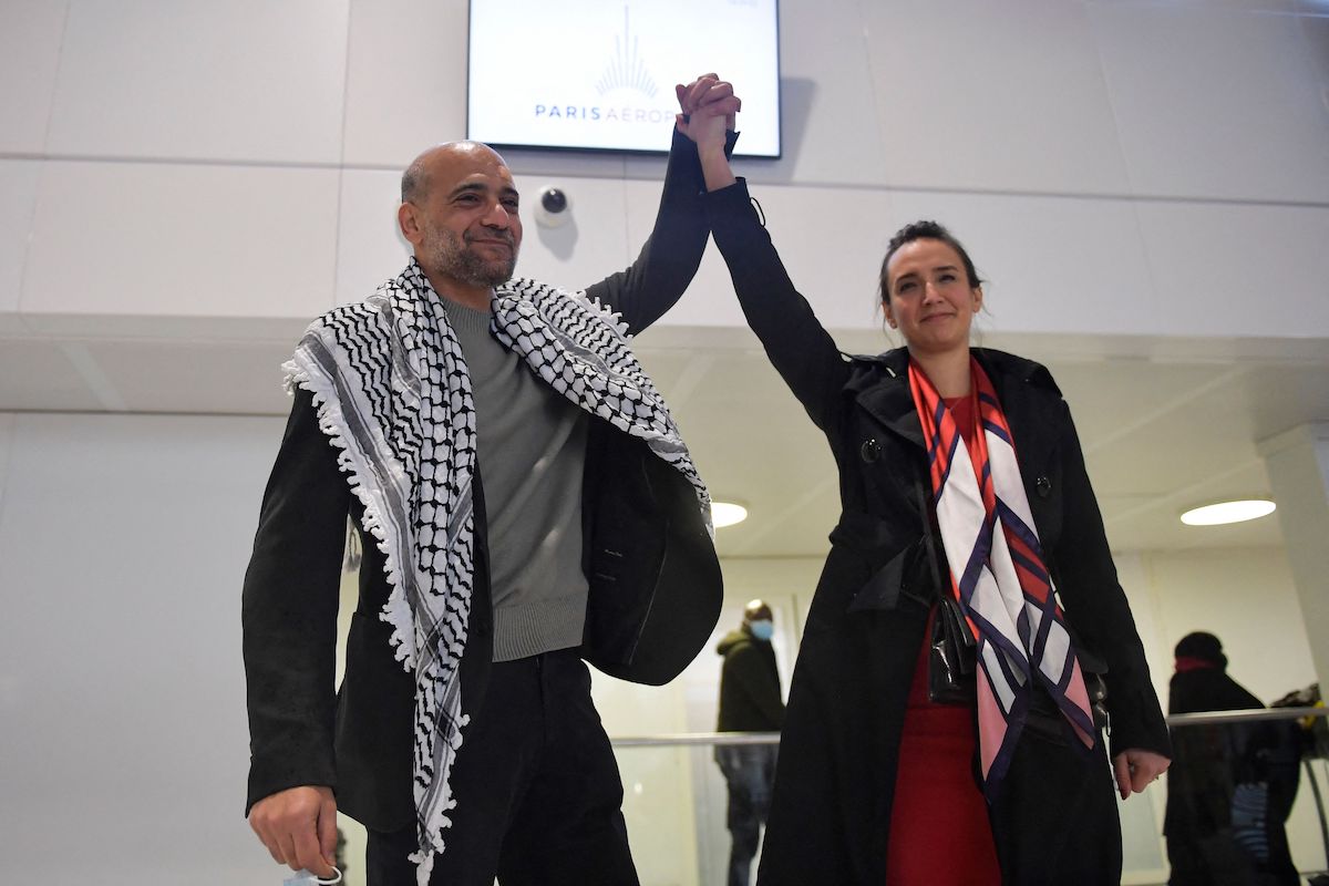 O ativista político egípcio-palestino Ramy Shaath (esq.) segura a mão de sua esposa, Celine Lebrun-Shaath, quando ele chega ao aeroporto Roissy em Roissy, nos arredores de Paris, em 8 de janeiro de 2022, após ter sido detido no Egito por mais de dois anos [Julien de Rosa/AFP via Getty Images]
