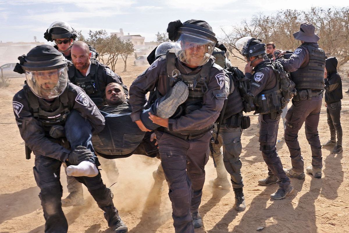 Polícia israelense prende manifestante na aldeia de Sawe al-Atrash, no deserto do Negev, durante ato contra um projeto de florestamento desenvolvido pelo Fundo Nacional Judaico (FNJ), em 12 de janeiro de 2022 [AHMAD GHARABLI/AFP via Getty Images]

